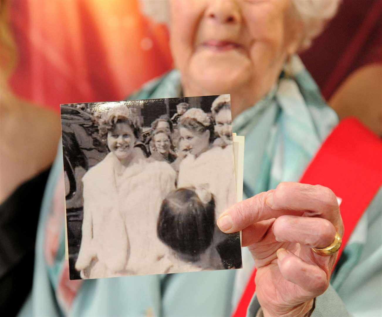 1953 flower queen Jean Toolley holds a black and white photo from the parade