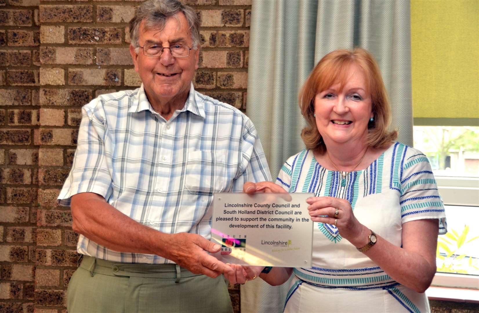 Chris Schofield and Councillor Elizabeth Sneath are pictured at Pinchbeck Village Hall, unveiling a Lincolnshire County Council Community Grant plaque