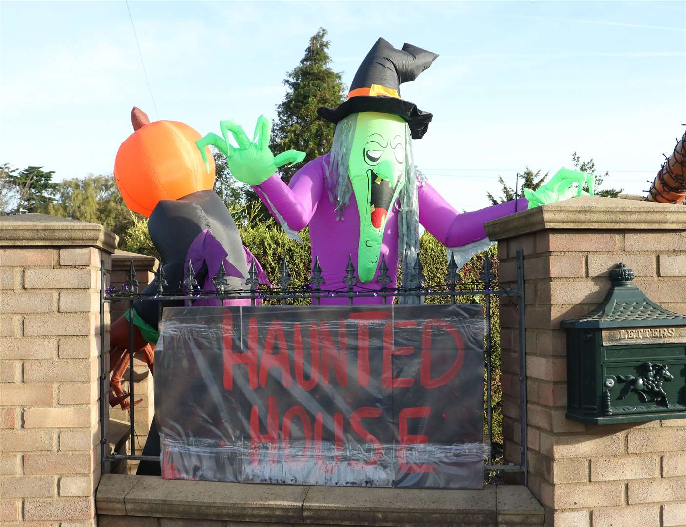 An inflatable witch peers over the wall