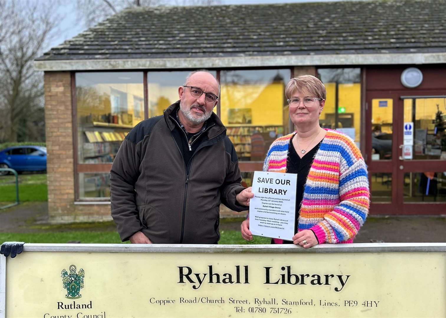 Kevin Corby and Deborah Rolfe holding the petition outside of Ryhall Library