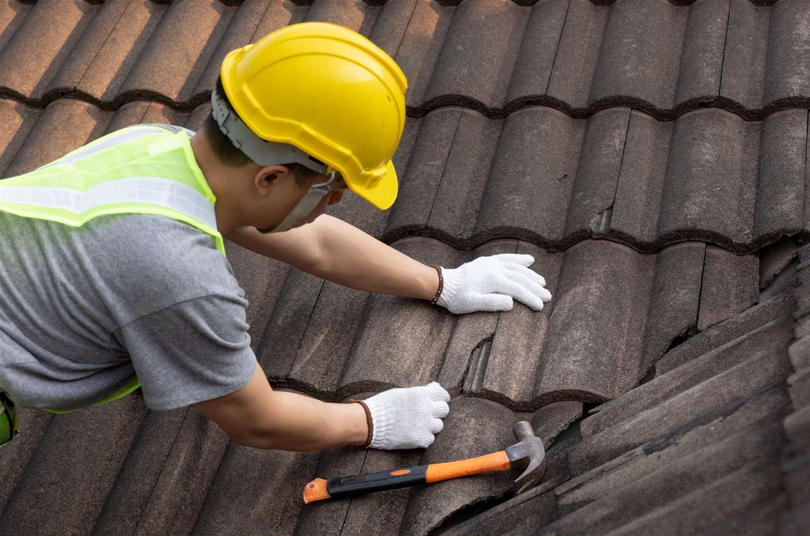 Worker replaces a tile on an old roof. Photo: istock
