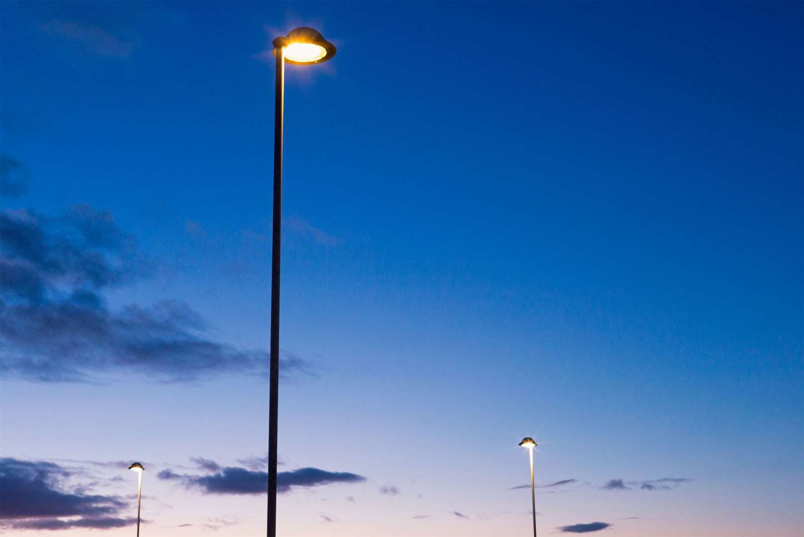 Street lamps illuminated just above the horizon, photographed against a darkening sky.