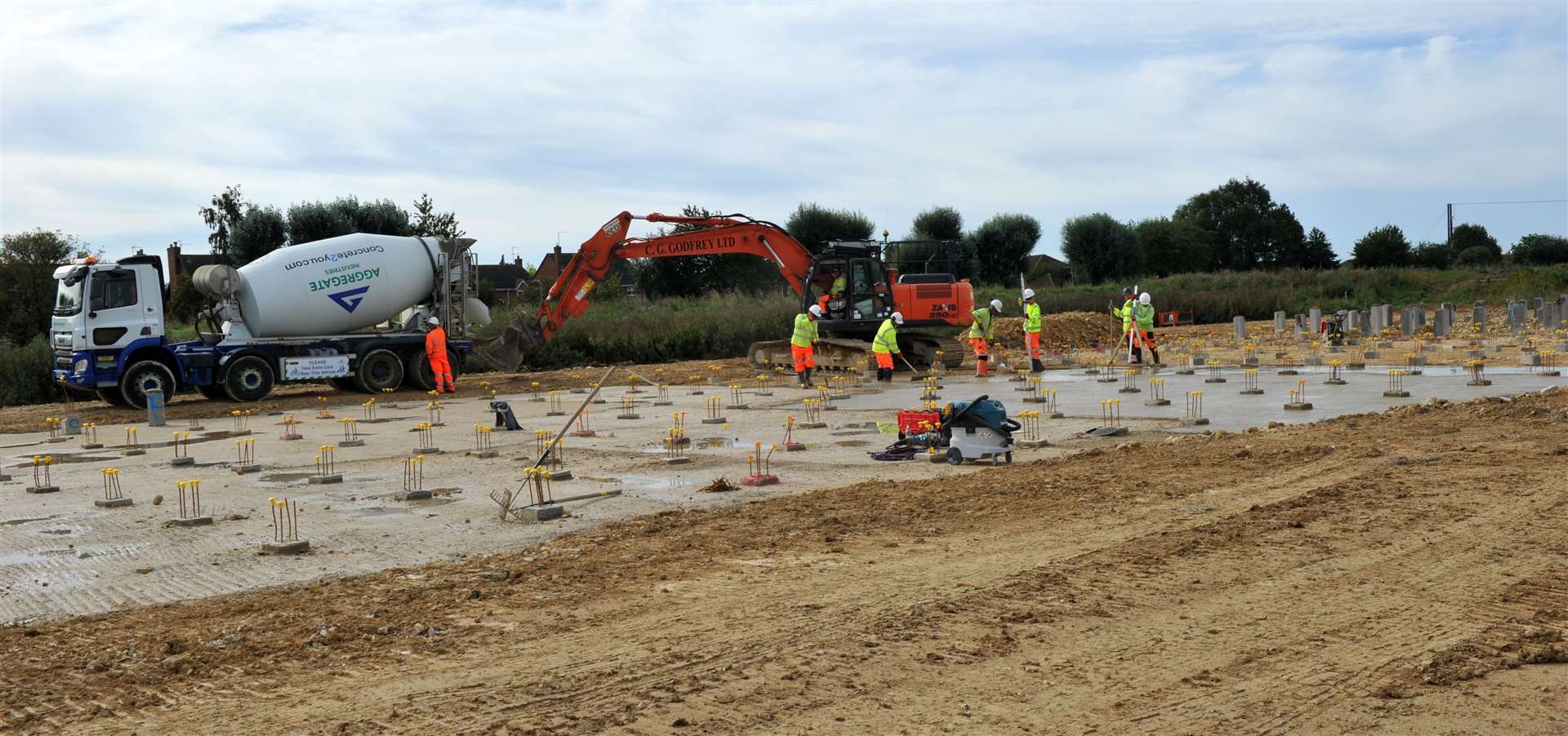 Workers are busy precisely laying concrete around the piles