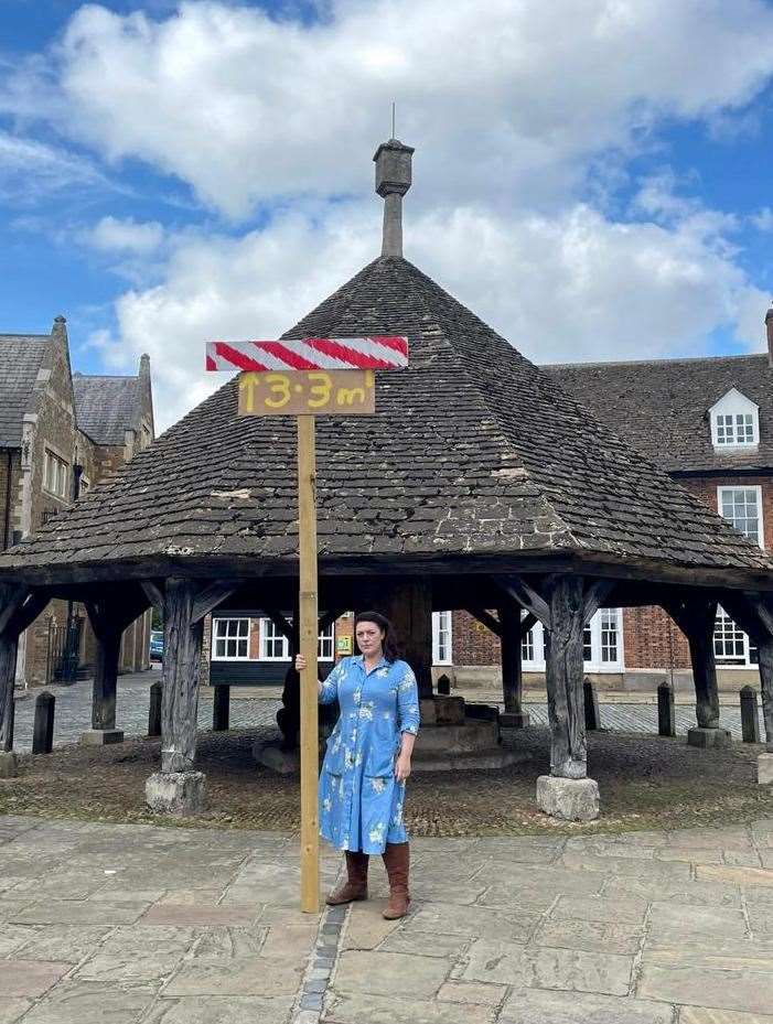 Rutland MP Alicia Kearns demonstrates the proposed height of the panels at the Mallard Pass Solar Farm at Oakham Buttercross