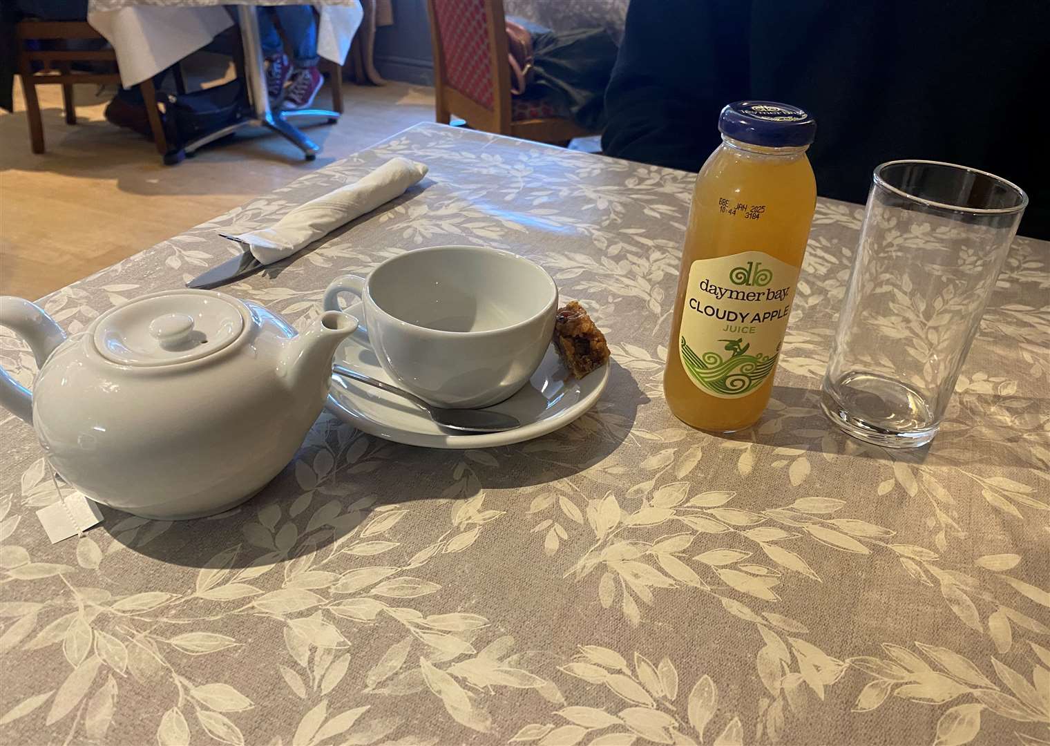 A pot of green tea, with a side of flapjack and cloudy apple juice