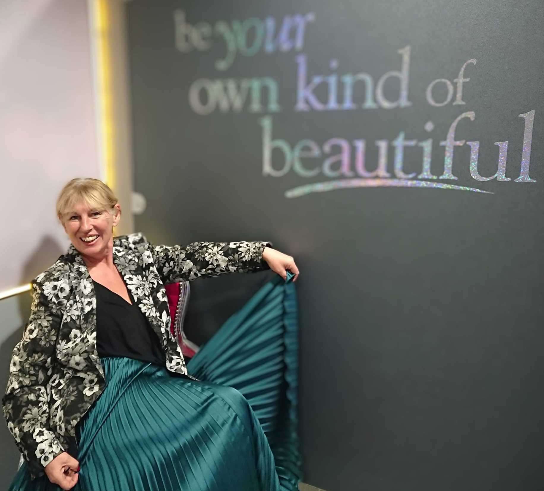 Kim posing in front of the ‘be your own kind of beautiful’ sign