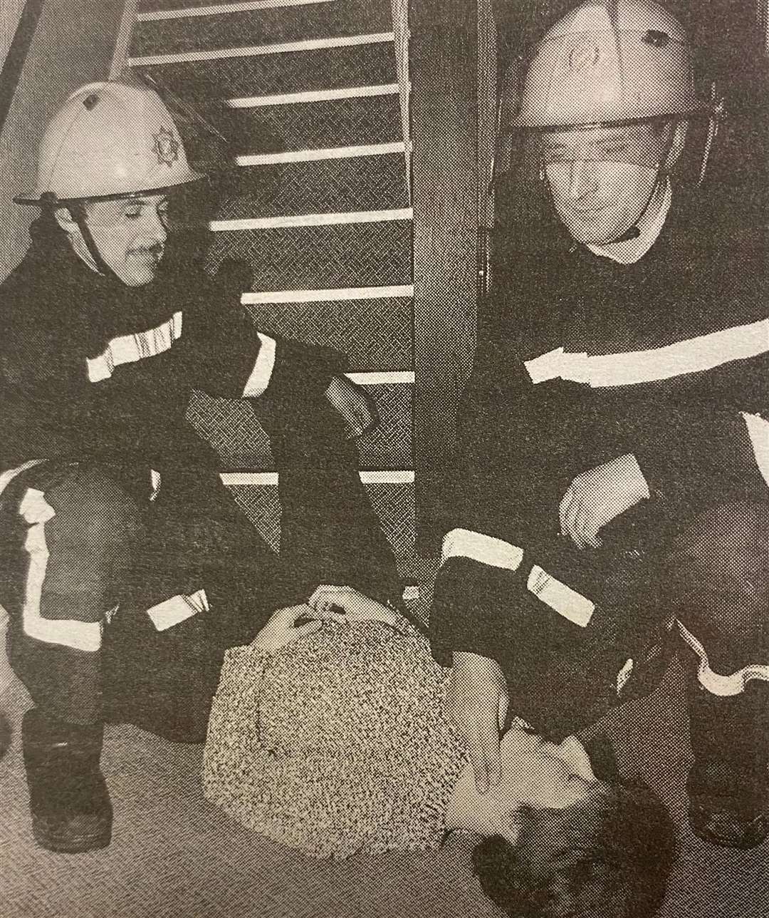 Firefighters attend to a woman at the bottom of the stairs 25 years ago.