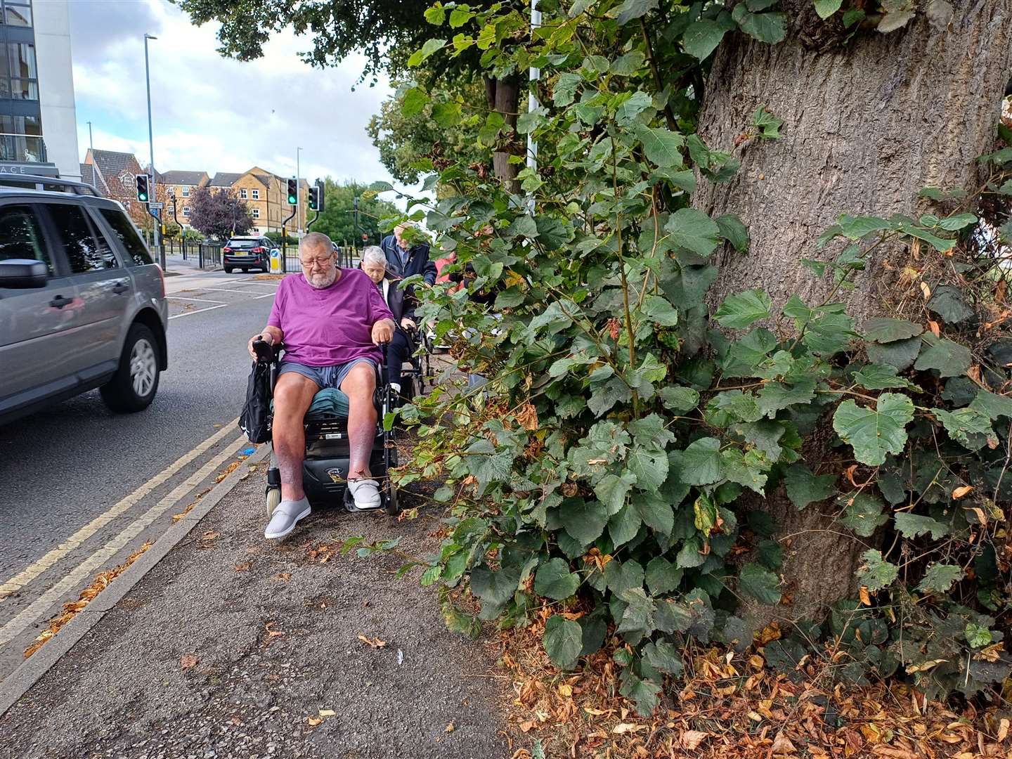 Pete Pretlove demonstrates how close residents get to both the edge of the footpath, risking falling into the road, and the traffic that passes by. Photo Daniel Jaines