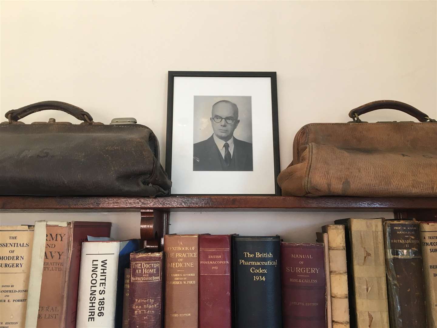 A picture showing Dr John Galletly along with some old medical books and bags